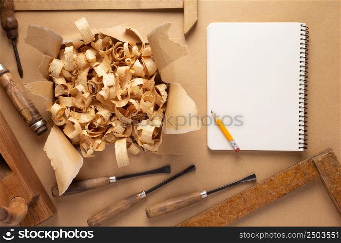 Woodworking carpenter chisel tool and wood shavings at paper background. Chisel as joiner tool