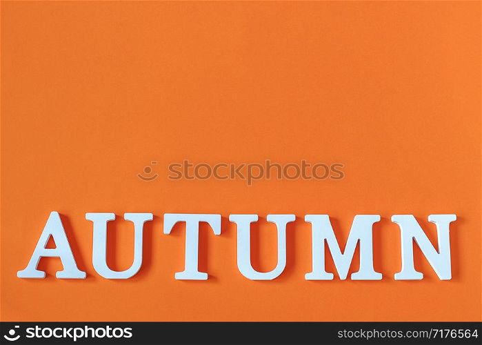 Word Autumn from white letters with copy space on orange paper background, minimal style. Concept Hello fall. Creative Top view Flat lay.. Word Autumn from white letters with copy space on orange paper background, minimal style. Concept Hello fall. Creative Top view Flat lay