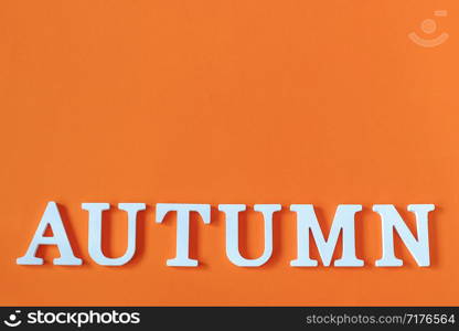 Word Autumn from white letters with copy space on orange paper background, minimal style. Concept Hello fall. Creative Top view Flat lay.. Word Autumn from white letters with copy space on orange paper background, minimal style. Concept Hello fall. Creative Top view Flat lay