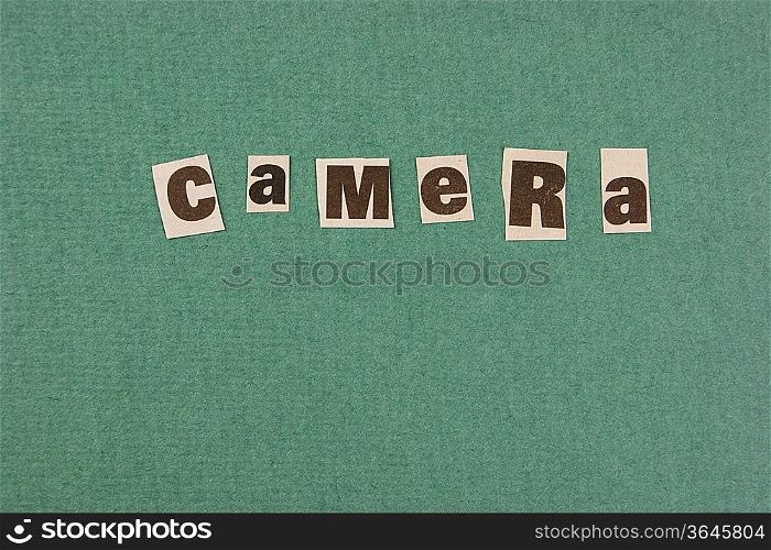 word cemera cut from newspaper on green background