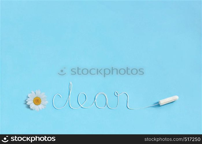 Word CLEAN from white thread hygienic female tampon and chamomile on blue background. Concept hygiene and health women and adolescents during menstrual cycle. Flat Lay, copy space. Word CLEAN from white thread hygienic female tampon and chamomile on blue background.