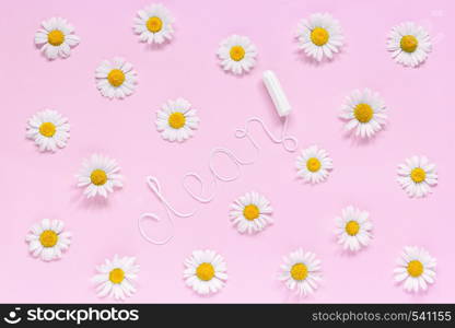 Word CLEAN from white thread hygienic female tampon surrounded by chamomile flowers on pink background. Concept hygiene and health women and adolescents during menstrual cycle. Flat Lay. Word CLEAN from white thread hygienic female tampon and chamomiles on pink background