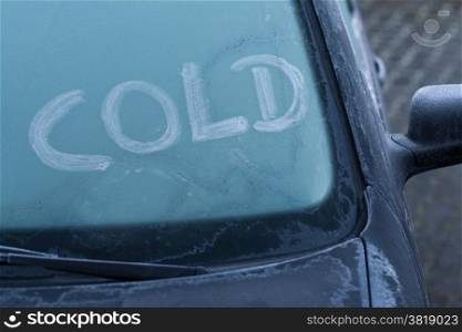 Word cold on a frozen window of a car