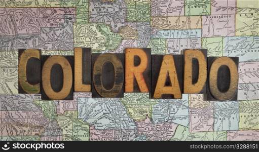 word Colorado in antique letterpress wooden type stained by ink over a vintage (eighty years old) faded map of the state