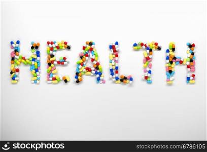 Word health made of colorful pills and capsules on white background. 3d render
