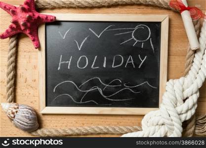 "Word "Holiday" written on blackboard decorated by seashells and marine knots"