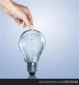 word Information inside a light bulb. Human hand putting word Information inside a light bulb