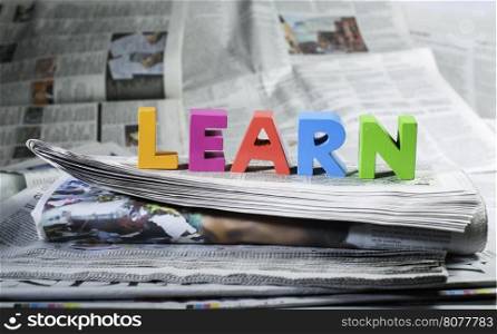 Word learn on newspaper. Wooden letters