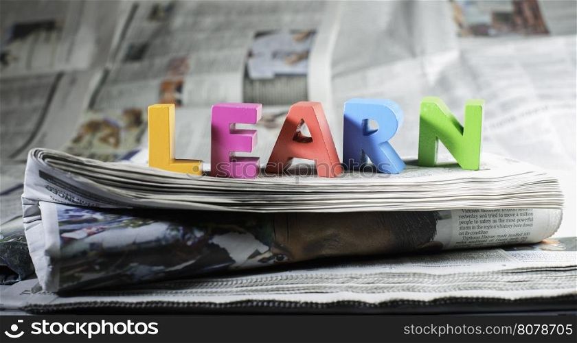 Word learn on newspaper. Wooden letters