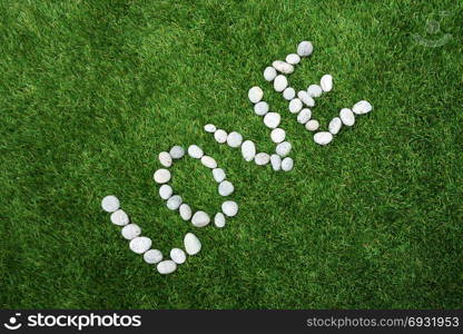 Word love made of pebble stones on green grass