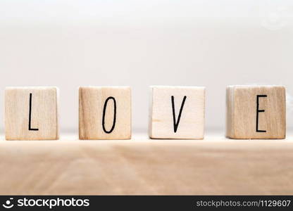 Word Love on wooden cubes with red heart, close-up near white background valentine concept. Word Love on wooden cubes with red heart, close-up near white background