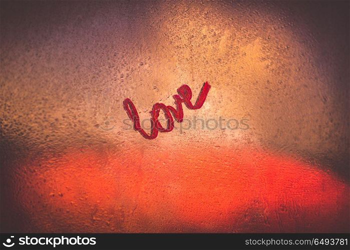 Word love written on the rainy window glass in the evening, sexy romantic message, happy Valentines day holiday. All you need is love