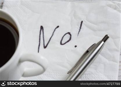 Word NO on napkin. No answer written on napkin and coffee cup on wooden table