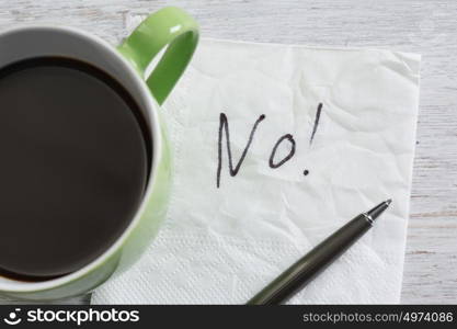 Word NO on napkin. No answer written on napkin and coffee cup on wooden table