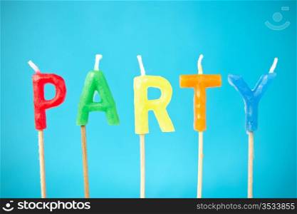 "word "Party" made from color candles on blue background"
