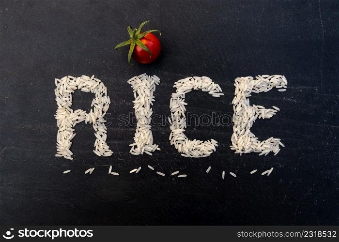 Word rice written with white grains on black slate board. Word rice written on slate