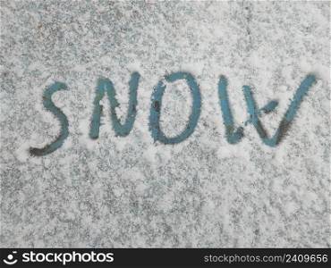 Word snow is written in snow on an old painted surface