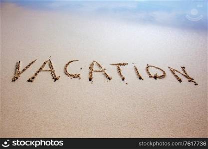 Word vacation written in a sandy tropical beach with soft sea wave. Vacation written on beach