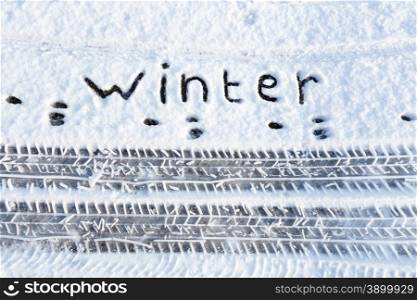 Word winter and tire tracks in snow during winter season