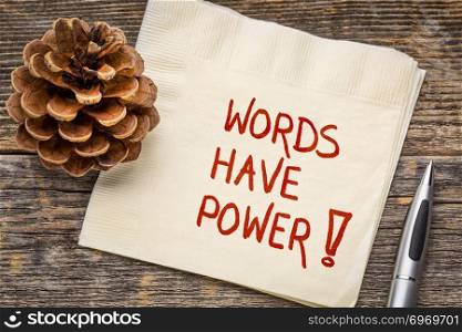 Words have power - handwriting on a napkin with a pine cone against rustic wood
