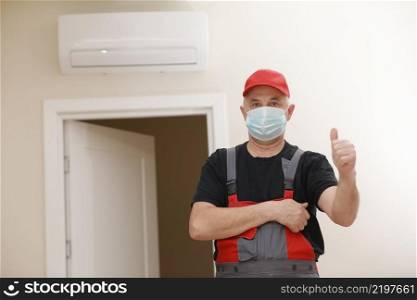 Work are done. Portrait of worker man with medical mask in red overall, black t shirt , red cap looking in camera and giving a thumbs up. white background, indoor studio shoot isolated. Work are done. Portrait of worker man with medical mask in red overall, black t shirt , red cap looking in camera and giving a thumbs up. white background, indoor studio shoot isolated.