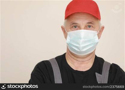 Work are done. Portrait of worker man with medical mask in red overall, black t shirt , red cap looking in camera. white background, indoor studio shoot isolated. Work are done. Portrait of worker man with medical mask in red overall, black t shirt , red cap looking in camera. white background, indoor studio shoot isolated.