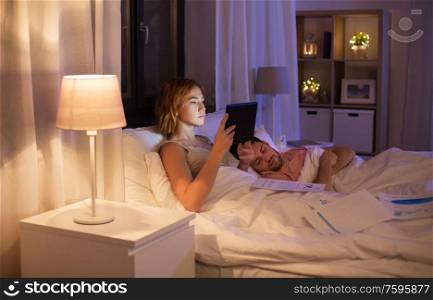 work, deadline and people concept - woman with tablet computer and papers working in bed at night. woman with tablet computer working in bed at night