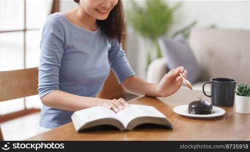 Work from home concept, Business women is reading book and eating dessert to relax in living room.