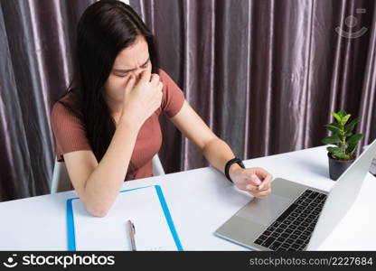 Work from home, Fatigued or strain Asian business young beautiful woman sits on desk workspace feeling tired stressed hold his nose close eyes after see screen long time of laptop computer at office