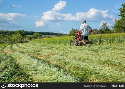 Work on an agricultural farm. A red tractor cuts a meadow.. Work on an agricultural farm