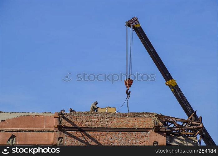 Work on the building repair, demolition of old elements. Descent lifting operation using a crane.. Work on the building repair, demolition of old elements. Descent