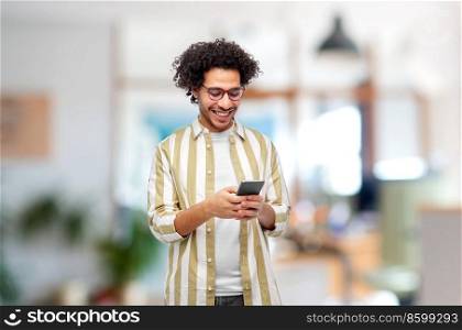 work, people and technology concept - happy smiling man in glasses with smartphone over office background. happy smiling man in glasses with smartphone