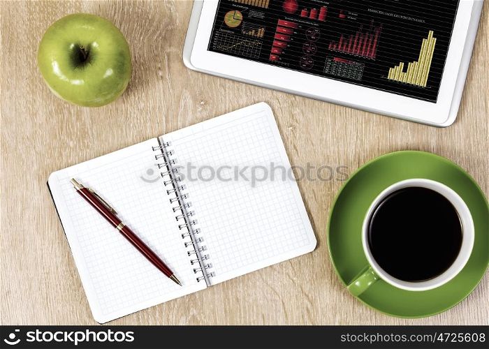 Work place. Tablet pc cup of coffee and notepad at table