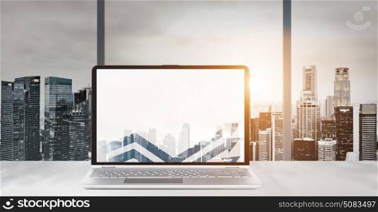 Work place with panoramic view. Laptop on table in office with panoramic sunset view of modern downtown skyscrapers at business district