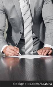 Work process and deal concept. Businessman with pen in hand reading official business contract before making a deal and signing document, close up view. Businessman signing contract document