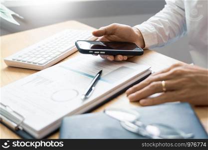 Work process concept, Business man using mobile phone writing in agenda consulting on a desk at home or office