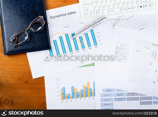 Work surface of office desk with graphic diagrams pen and keyboard. Graphic charts, ballpoint pen and keyboard on the table