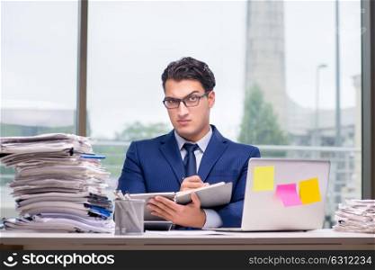 Workaholic businessman overworked with too much work in office. The workaholic businessman overworked with too much work in office