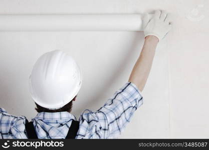 worker attaching wallpaper to wall