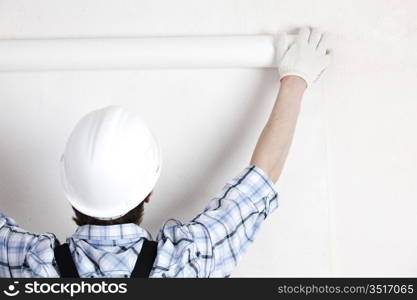 worker attaching wallpaper to wall