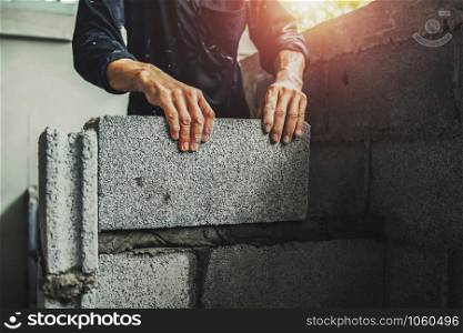 Worker building wall bricks with cement