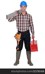 Worker carrying an aluminium plank and a toolbox