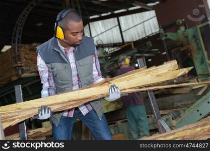 Worker carrying lengths of wood
