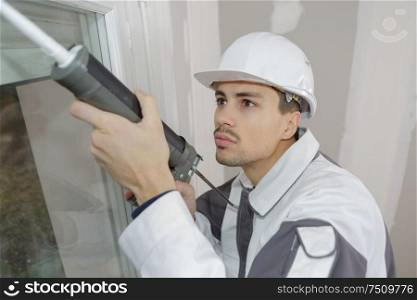 worker caulking with silicone door
