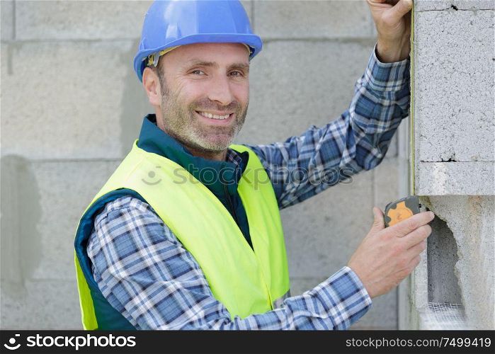 worker checks erected brick wall with level