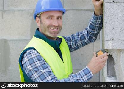 worker checks erected brick wall with level