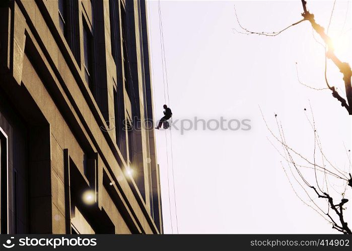 worker cleaning outdoor windows service on high rise building