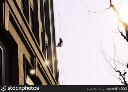 worker cleaning outdoor windows service on high rise building