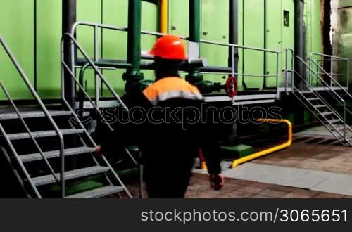 worker climbs stairs and goes away to platform inside turbo pumping unit of gas compressor station