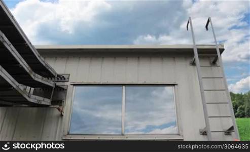 worker climbs up metal ladder to house and goes out on roof